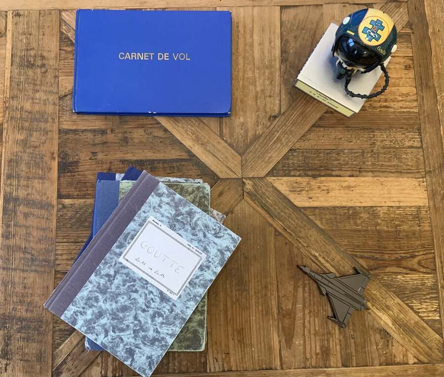 Carnets de vol, casque et maquette de Rafale sur une table en bois